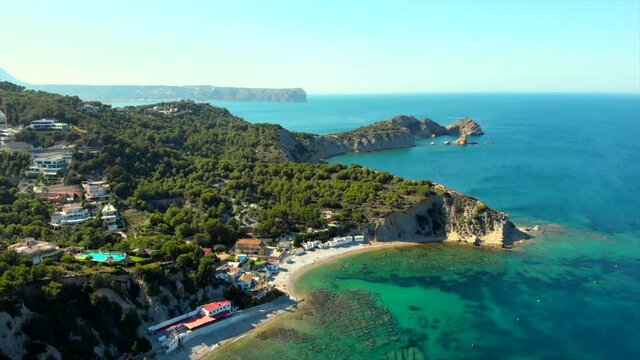 Real time drone point of view Costa Blanca picturesque coastline. Turquoise lagoon, clear Mediterranean Sea waters, sunny day. Spain