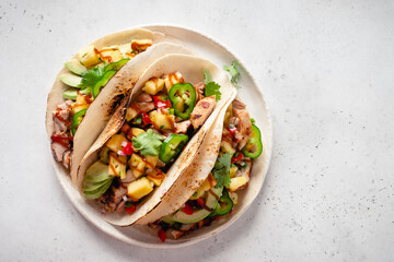 Taco tortillas filled with barbecue chicken and topped with pineapple salsa