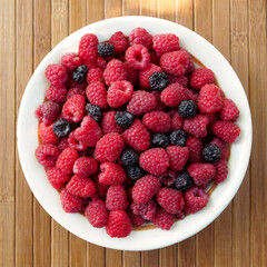 Mix of red and black raspberries on a white plate