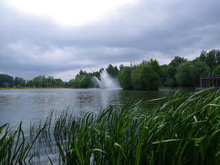 Fountain on the pond, plants and trees in the city Park. A place to relax in a city Park.