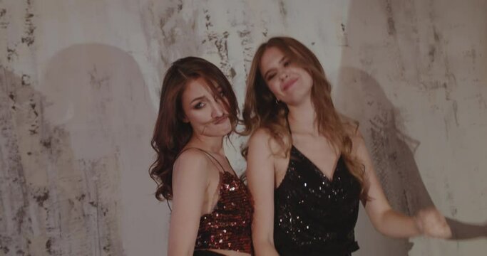 Two pretty models having a fun when posing in stylish clothes on background