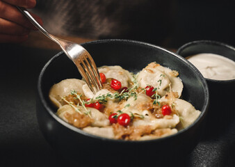 Dumplings with herbs and berries in plate on dark background, healthy food