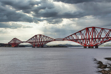 Iconic Forth Bridge from South Queensferry, Scotland, with dramatic cloudy sky