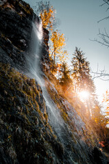 Wonderful and beautiful waterfall in the german mountains with golden autumn tones on a bright sunny day. Wild mountain river with water splash. Harz Mountains, Harz National Park in Germany.