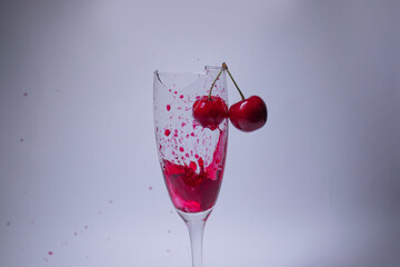 drops of red liquid - blood - in a broken champagne glass with a cherry on it on a white background. Isolated. Copy space. pain concept. High quality photo