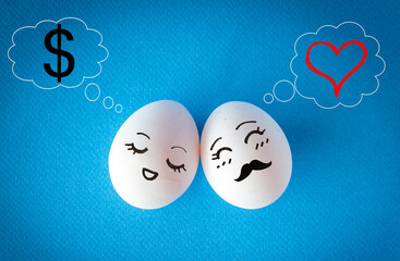 Faces on the easter eggs, money vs. love concept with heart and dollar sign on blue background