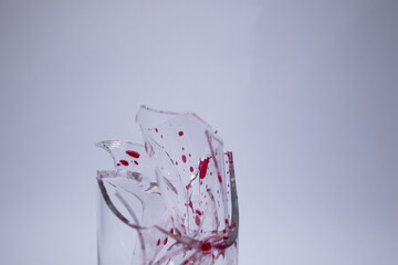 drops of red liquid - blood - on the fragments of a broken glass in a broken glass on a white background. Isolated. Copy space. pain concept. High quality photo