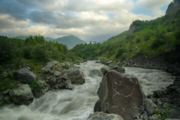 Mountain river stream landscape with dramatic cloudy sky at sunset