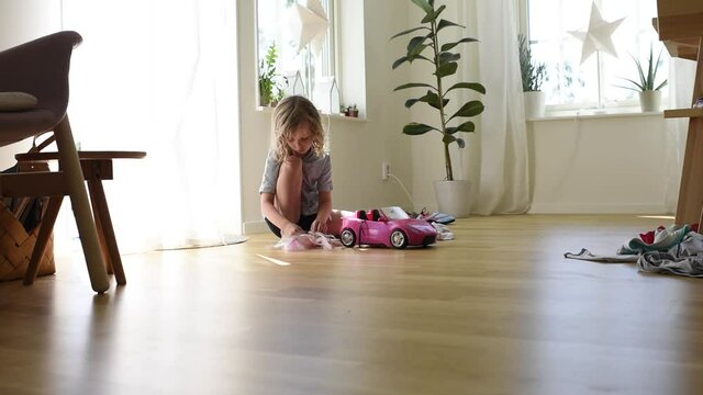 young girl playing with her barbies on the floor at home