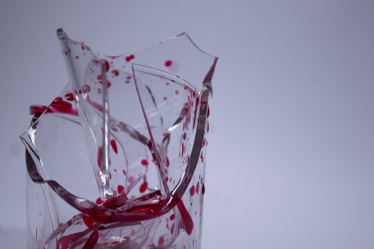 drops of red liquid - blood - on the fragments of a broken glass in a broken glass on a white background. Isolated. Copy space. pain concept. High quality photo