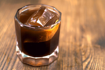 A glass of coffee on wooden background. Iced americano in cafe. Cool summer drinks. Whiskey coctail, coffee-based alcohol cocktails and long drinks serve.