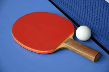 Table Tennis Paddle and ball near net on the blue table