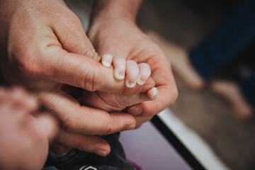 The handle of a newborn baby is held by dad's fingers