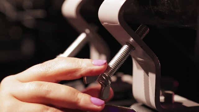 A female hand fastens a screw on a soffit hanging on a shank