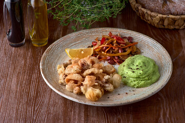 small octopuses in batter with mashed potatoes and vegetable saute close up. The traditional Mediterranean food.