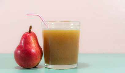 Pear juice and fruit on green surface on pink background