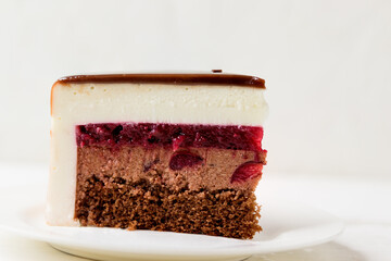Delicate cake with chocolate cream, cherry jam on a white background. Piece of cake.