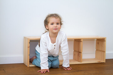 Little cute girl in a bright room, a minimum of objects in the room, the child rejoices, sitting on...