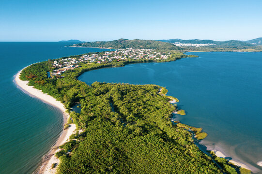 Brazil, Florianopolis. Panoramic aerial view of Daniela beach pontal peninsula and river showing sea, sand, trees and an the village.