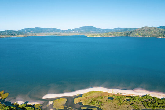 Brazil, Florianopolis. Panoramic aerial view of Daniela beach pontal peninsula and river showing sea, sand, vegetation and an small internal lake.