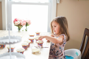 little girl decorating cupcakes