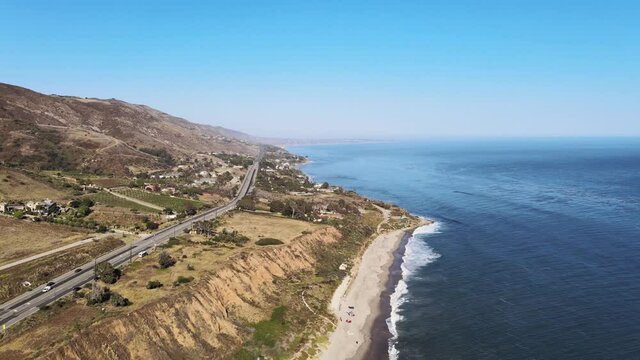 Drone shot moving along pacific ocean coast in Malibu on a beautiful summer day