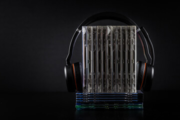 Hi-Fi headphones on stack of CDs on black background