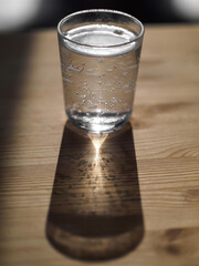 A clear glass of mineral water on a wooden table.