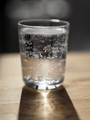 A clear glass of mineral water on a wooden table.
