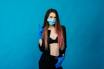 Cheerful and joyful young female playing with protective medical mask and gloves on blue background. Close-up portrait. End of coronavirus quarantine.