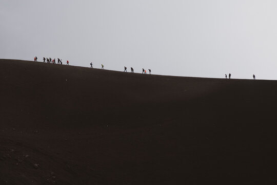 
ETNA NATIONAL PARK, SICILY, ITALY row of tourists walking on the edge of a crater an altitude of 2900 m., at the border with the area of high criticality of the volcano.