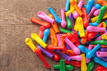 Pile of not inflated balloons different colors on the wood background.