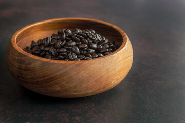 Fototapeta na wymiar Dark Roast Coffee Beans in a Wooden Bowl