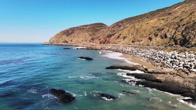 Drone shot moving over ocean along pacific highway in California on a beautiful summer day