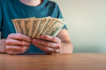 young man holding money US dollars in his house