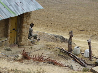 Campesino descansando  a la entrada de su casa, mientras mira el horizonte desierto, imagen...