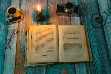 open book with candlelight, incorporates a camera, clock and a cup of coffee