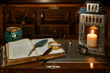 An open antique book in which a magnifying glass and a writing pen rest. are found on a wooden desk on leather. Two lighted lanterns are incorporated to illuminate with a candle