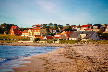 Beautiful Houses in typical yellow color on the beach with sea view during colorful sunset. Denmark, North Sea