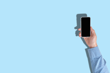 Person uses a smartphone on a blue background with top view and copy space.