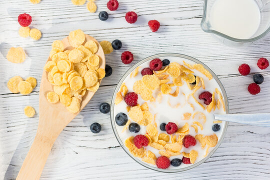 Healthy summer breakfast - cereal with milk and fresh berries in a bowl on the white wooden table. Healthy eating concept. Top view, flat lay