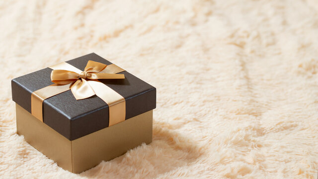 Beautiful golden box on a cream fur blanket. Surprises, gifts, discounts concept. Blank for advertising or design, copy space