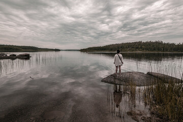 A lady is enjoying the beautiful lake view on a cloudy day- a perfect picture for yoga, mediation, relaxation themes