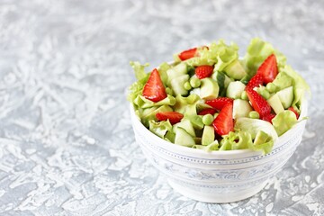 summer salad with strawberries, avocado, cucumber, green peas. copy space