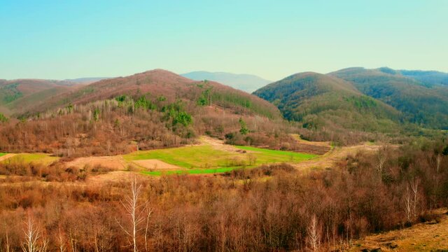 aerial view on valley surrounded hills and mountains spring season daytime filed with young plant deciduous leafless trees