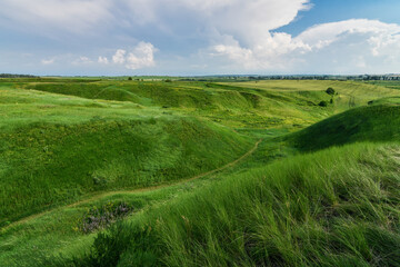 Breathtaking scenery of valley with green hills covered with grass. Blue sky background. Selective focus.