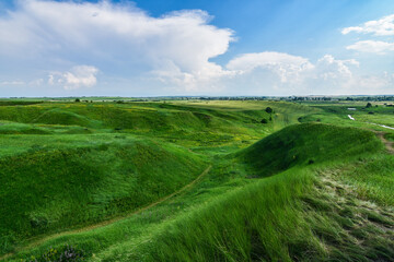 Breathtaking scenery of valley with green hills covered with grass. Blue sky background. Selective focus.
