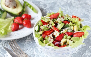 summer salad with strawberries, avocado, lettuce, onion,cucumber , green peas. dressed with balsamic sauce. copy space