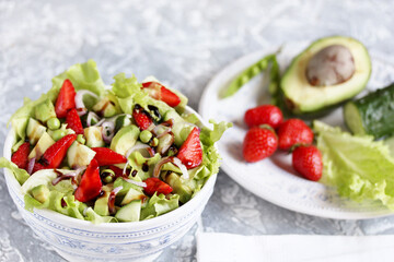 summer salad with strawberries, avocado, lettuce, onion,cucumber , green peas. dressed with balsamic sauce. copy space
