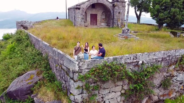 Aerial view of a group of friends on a mountain with a church in Galicia